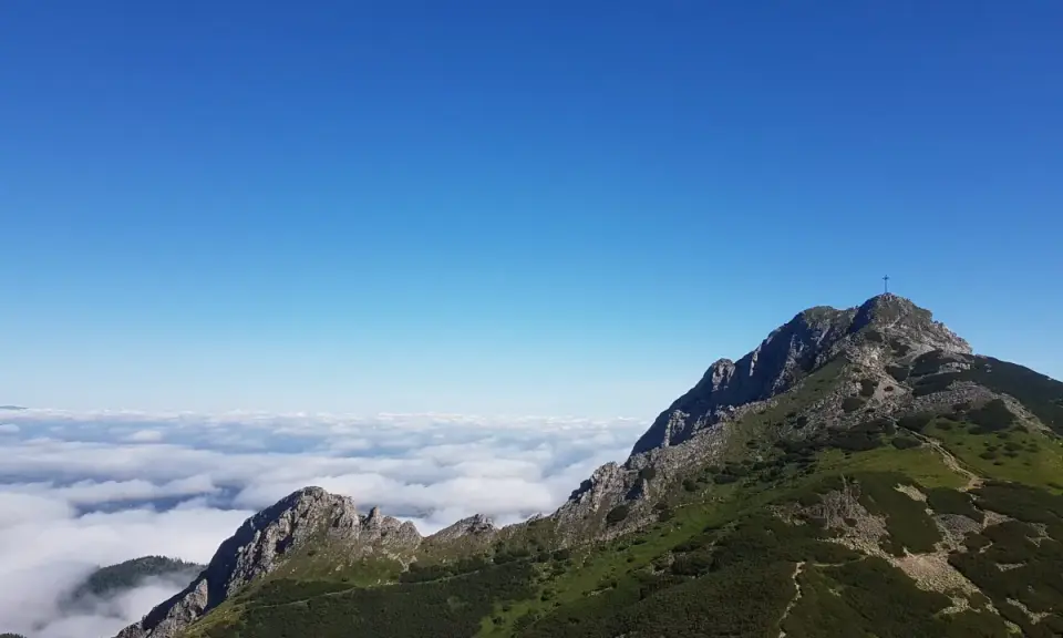 Giewont wysokość 1894 m n.p.m. widoczna z grani, morze chmur poniżej, błękitne niebo.