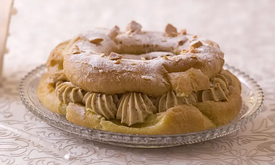 Un Paris-Brest rond, saupoudré de sucre glace et d'amandes effilées, garni d'une généreuse crème diplomate.