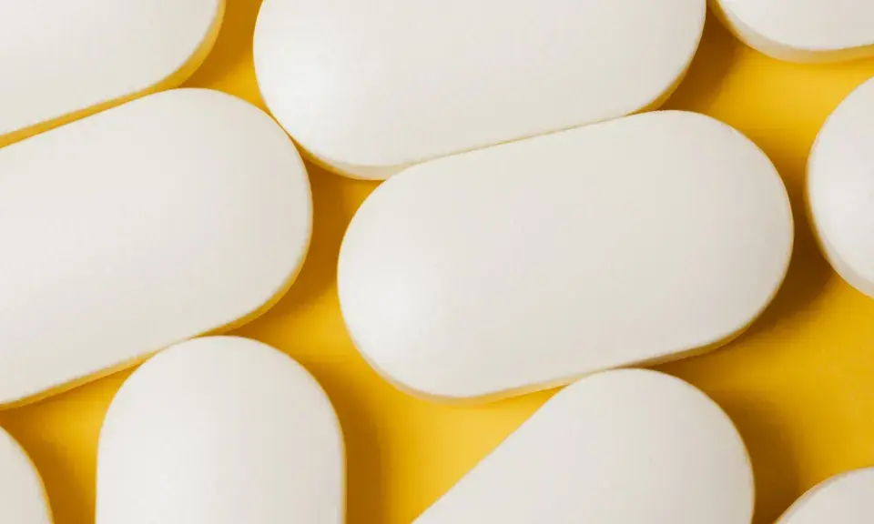 Bianche compresse ovali, disposte su sfondo giallo. Potrebbero essere un antibiotico azitromicina, utili per combattere infezioni batteriche.