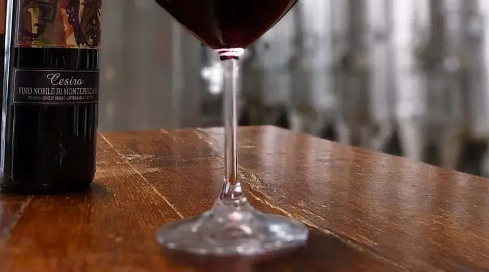 Bottiglie di Vino Nobile di Montepulciano e un calice di vino rosso, pronti per una degustazione vini toscana.