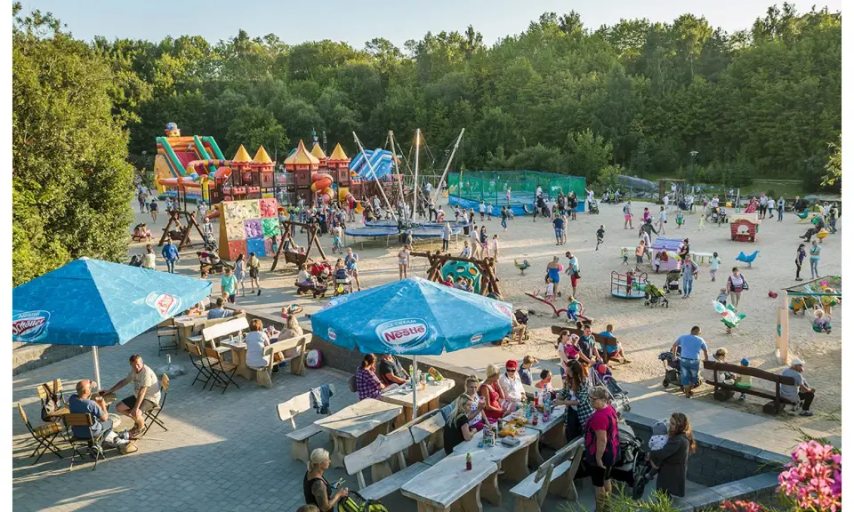 Rodzinna zabawa na placu zabaw w Ocean Park Władysławowo. Dzieci szaleją na dmuchanych zamkach, trampolinach i zjeżdżalniach, podczas gdy dorośli odpoczywają przy stolikach.