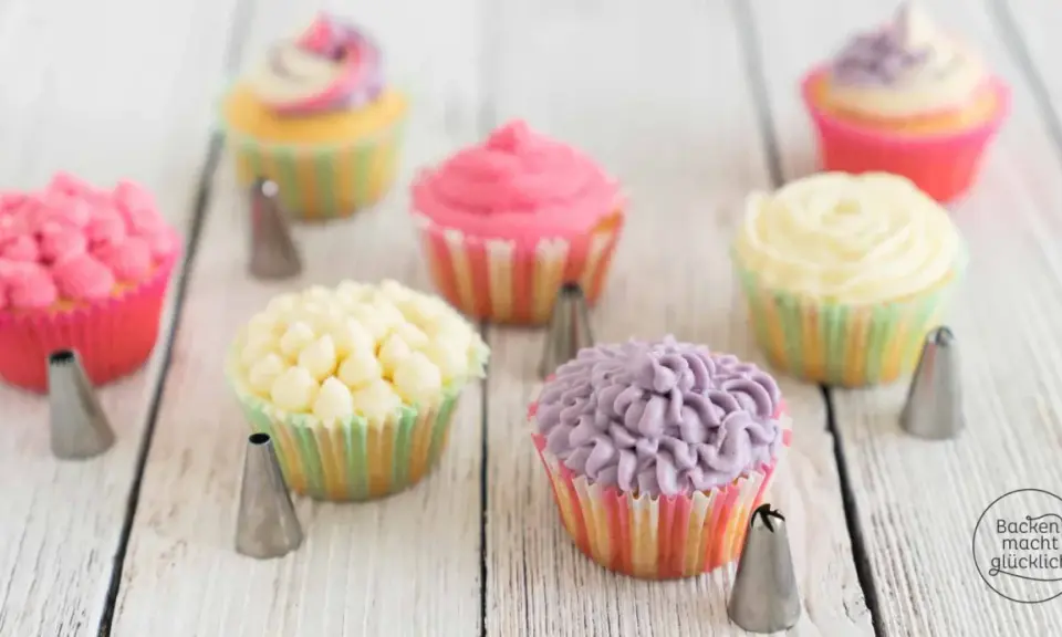 Bunte Muffins verzieren: Rosa, gelbe und lila Frosting-Kreationen mit Spritztüllen.
