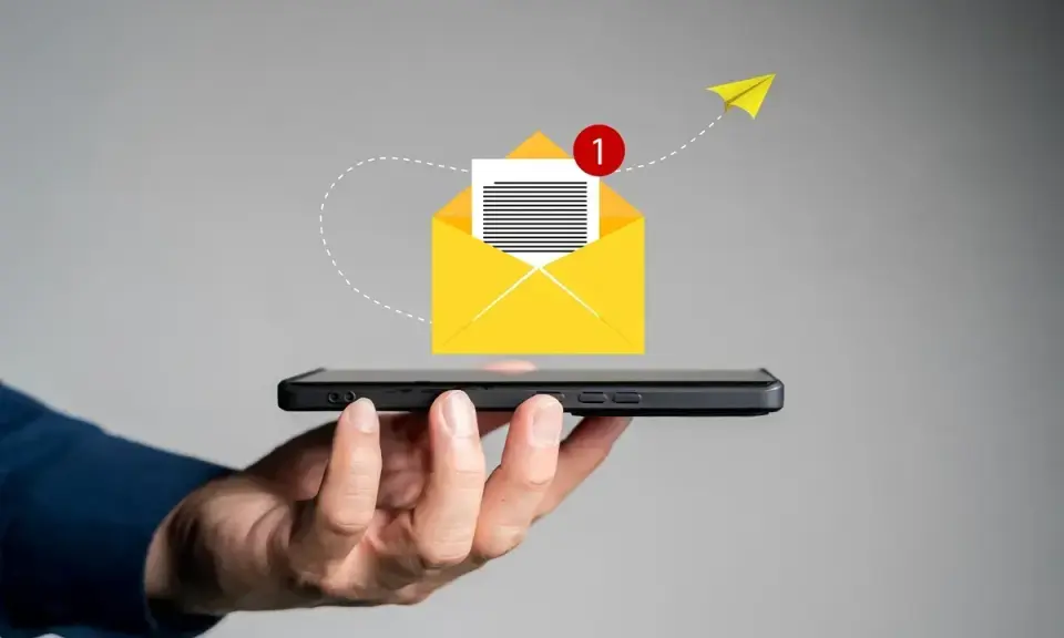 Dłoń trzyma smartfon, z którego wylatuje żółta koperta z powiadomieniem. Jak napisać SMSa o urlop na żądanie?