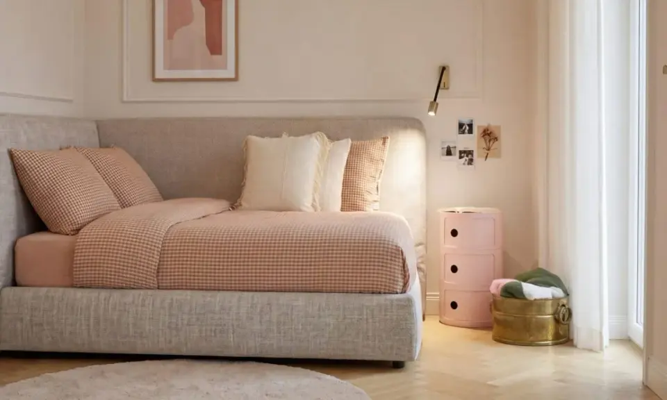 Camera da letto ragazza aesthetic: letto accogliente con biancheria a quadretti, cuscini morbidi, comodino rosa e decorazioni murali.