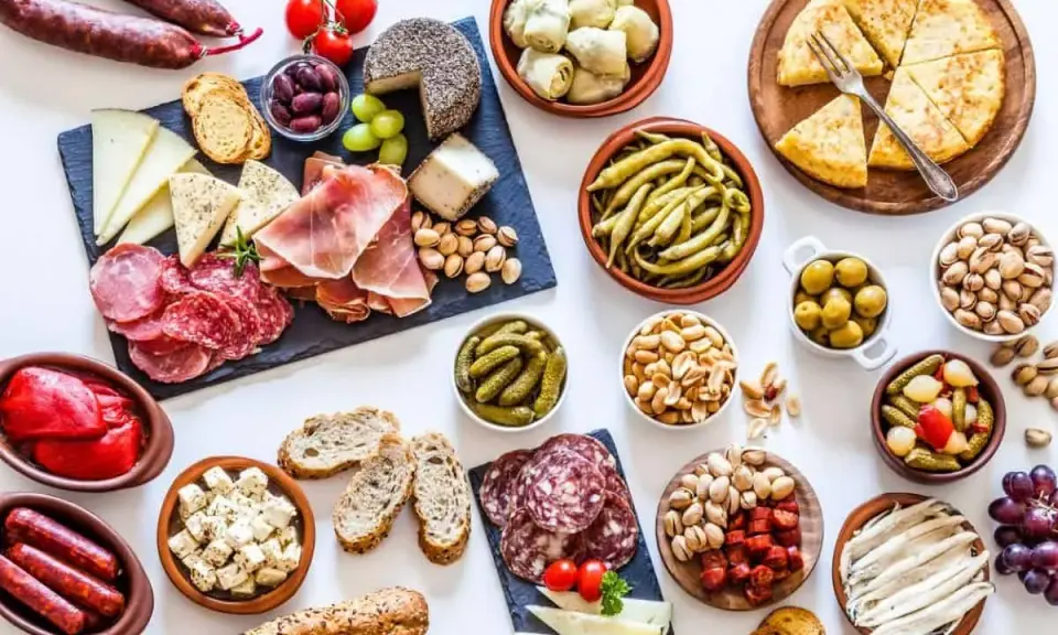 Un festin de tapas pour une pendaison de crémaillère : charcuterie, fromages, olives, cornichons, fruits secs et pain.
