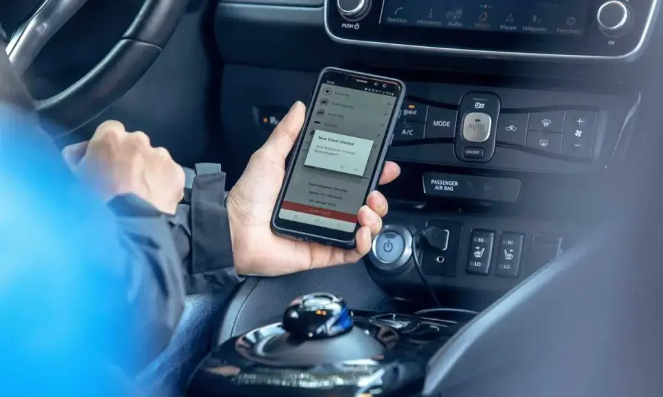 Mano che tiene uno smartphone con app di navigazione attiva, mostrando il **power cruise control** per un viaggio in auto.