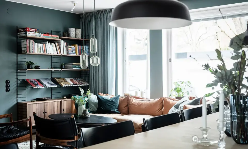 Vardagsrum med bokhylla i 50-talsstil, soffa i läder och stora fönster.