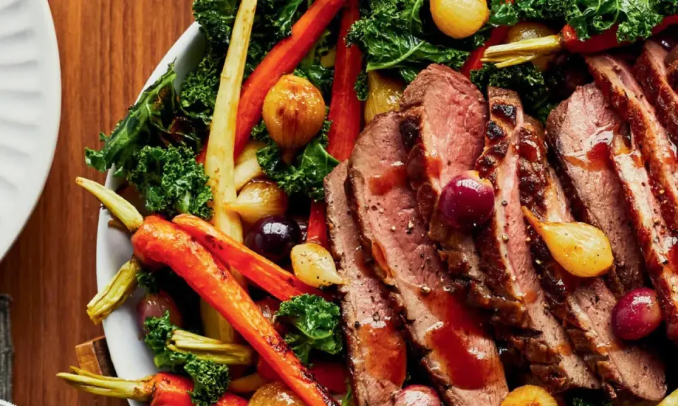 Tranches de magret de canard juteux, accompagnées de carottes rôties, d'oignons grelots et de chou frisé. Un plat savoureux et coloré.