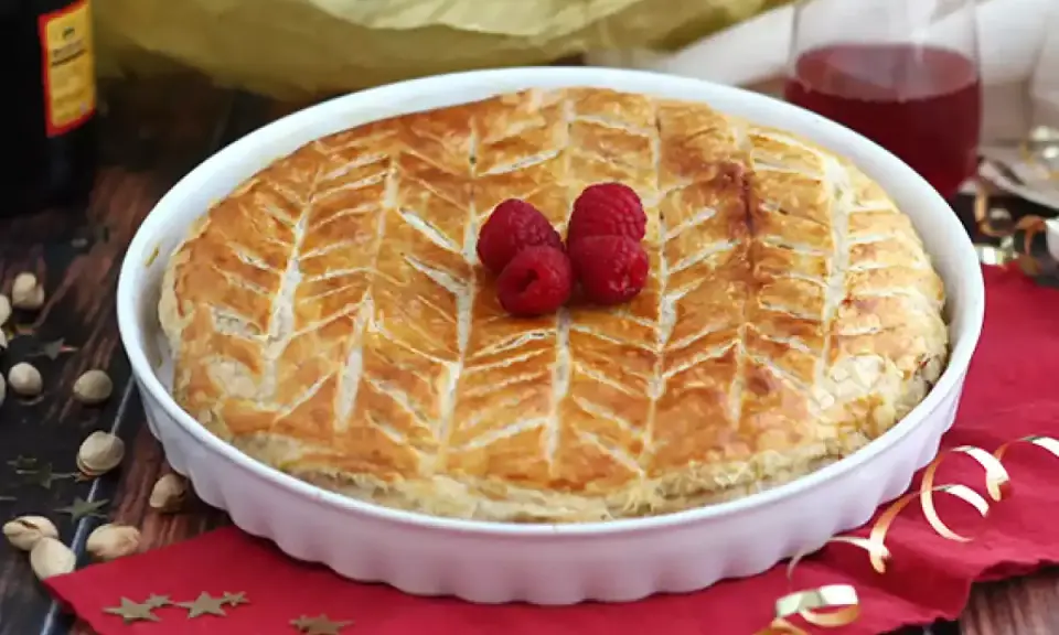 Une délicieuse galette pistache framboise dorée, décorée de fruits rouges frais, prête à être dégustée.