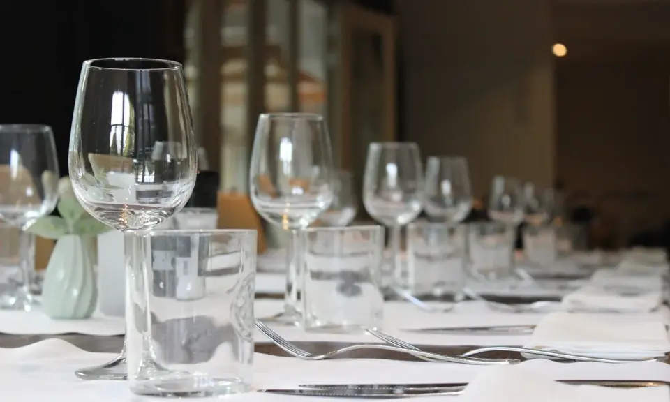 Un verre à eau et un verre à vin sont positionnés sur une table dressée, prêts pour un repas.