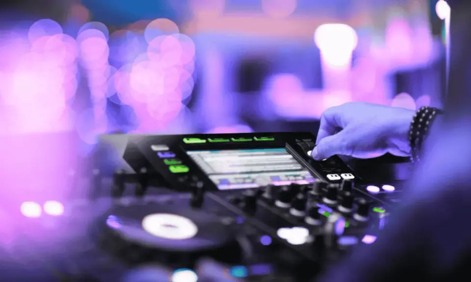 Mano su mixer, luci viola e rosa sfocate, creando l'atmosfera perfetta per la musica tech house.