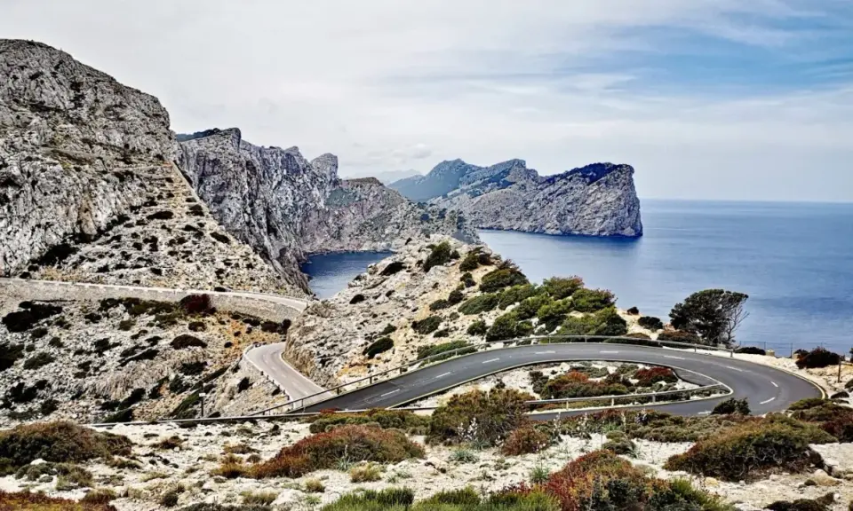 Carretera sinuosa en acantilados rocosos con vistas al mar azul. Un viaje en coche por un paisaje espectacular.