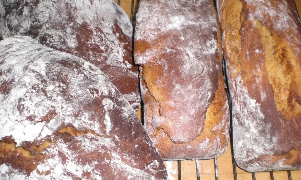 Nybakade sirapslimpor, pudrade med mjöl, redo att avnjutas. Ett perfekt sirapslimpa recept för hembakat bröd.