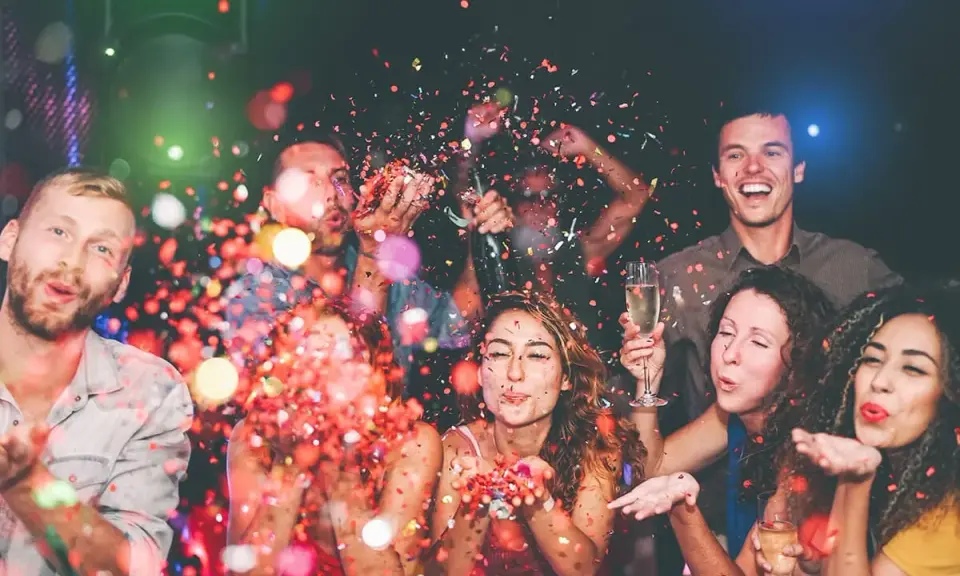 Gente celebrando con confeti y copas de champán. ¡Una fiesta perfecta para organizar despedida de soltero!