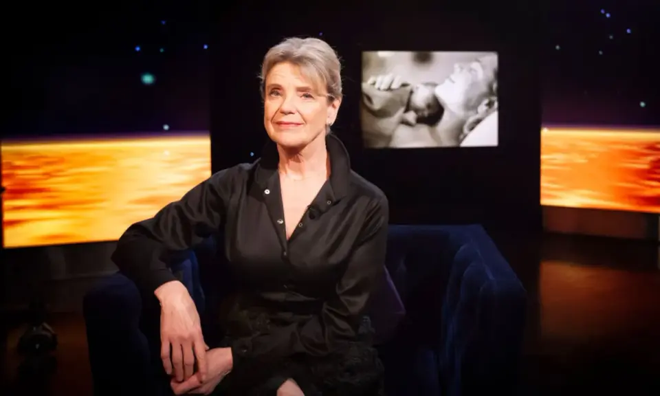 Stina Ekblad sitter i en mörkblå soffa, med en skärm bakom sig som visar klipp från filmer och tv-program med henne.