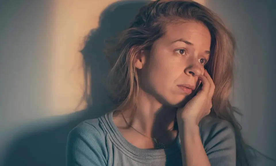 Une femme songeuse, le regard perdu, se demande : "suis je sous l'emprise d'un manipulateur test ?" Son visage exprime le doute et l'inquiétude.