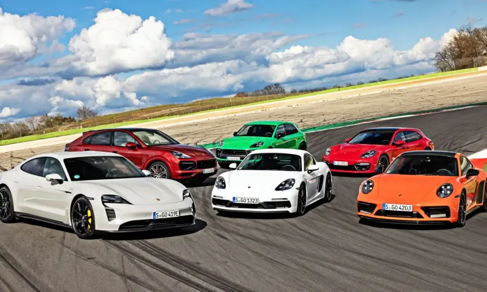 Różne rodzaje Porsche: biały Taycan, czerwony Cayenne, zielony Macan, biały Cayman, czerwona Panamera Sport Turismo i pomarańczowy 911 na torze wyścigowym.