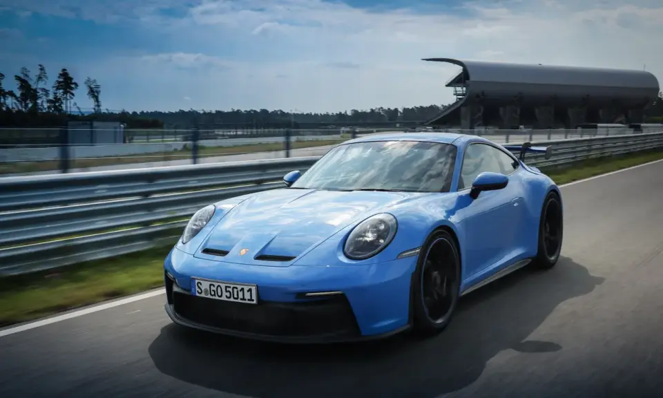 Ein blauer Porsche GT3 Rennwagen rast auf einer Rennstrecke.
