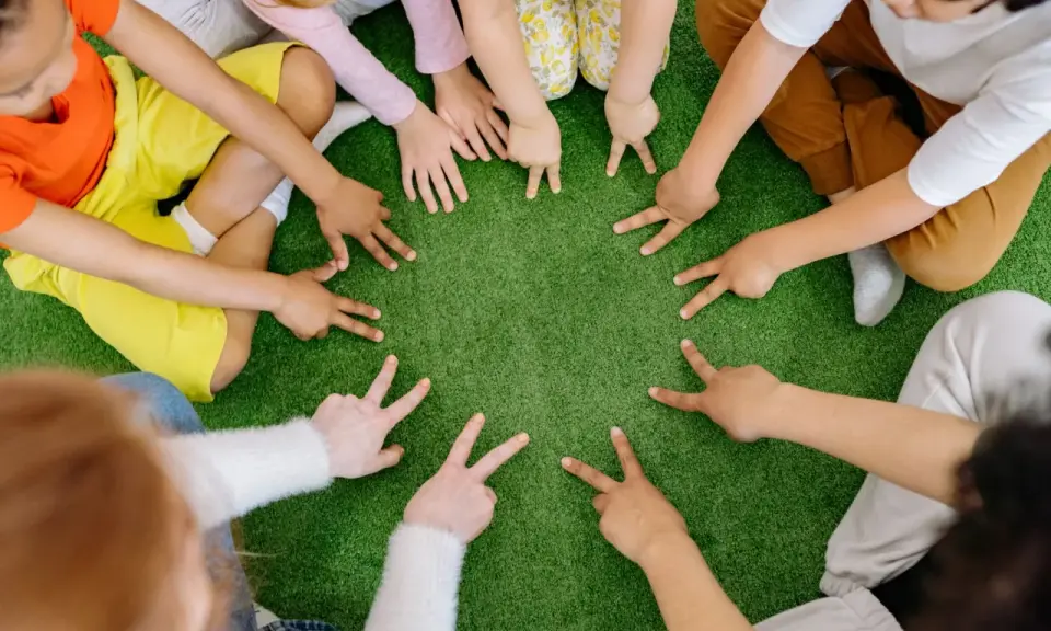 Dzieci tworzą krąg, pokazując palcami cyfry. To spokojne zabawy wyciszające Montessori, rozwijające koncentrację i współpracę.