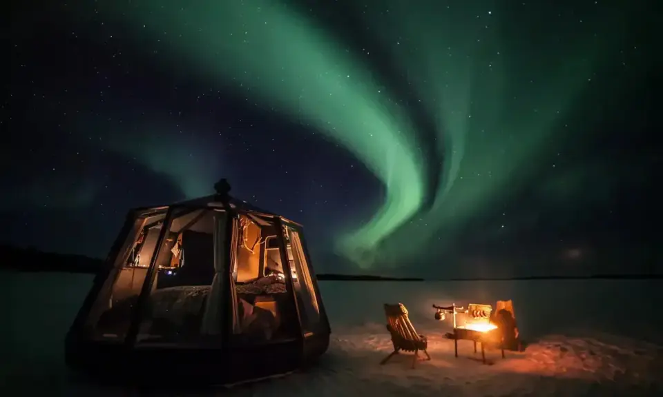 Drömmen att bo i igloo och se norrsken blir verklighet. En glaskupol med säng och en mysig eldstad utomhus under en magisk himmel.