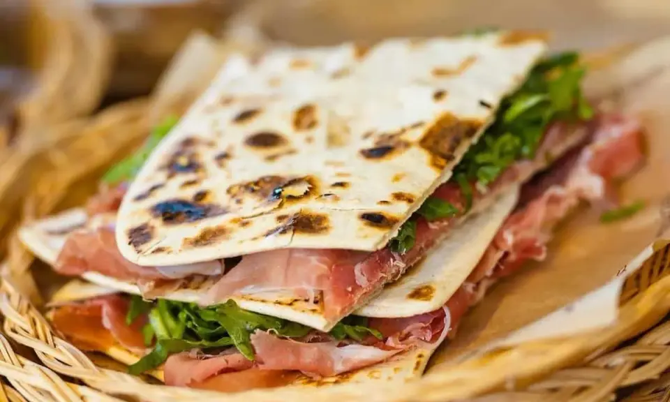 Piadina romagnola con prosciutto crudo e rucola, un'ottima opzione per chi cerca dove mangiare a Rimini.