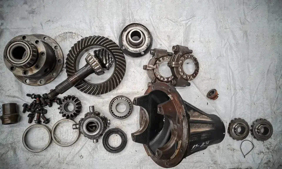 Rozłożony mechanizm różnicowy, widoczne koła zębate, łożyska i obudowa. Może to być wada usterka lub przygotowanie do naprawy.