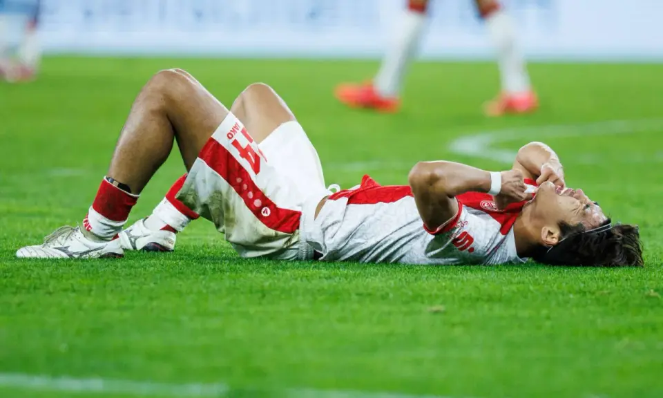 Fußballer liegt erschöpft auf dem Rasen, die Hände im Gesicht. Nach einem harten Spiel braucht er Regeneration.