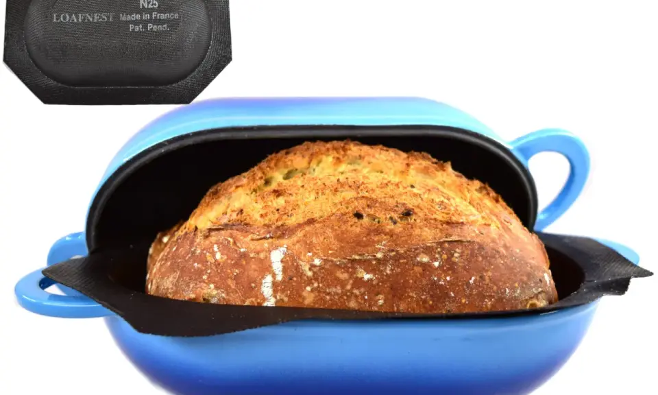 Pain doré dans une cocotte bleue, prêt pour la cuisson. Le couvercle noir avec "LOAFNEST" suggère une cuisson parfaite, chaleur tournante ou pas.