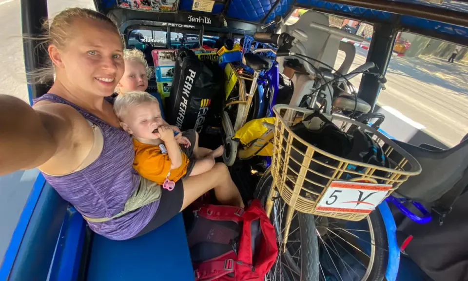 Familj i tuk-tuk med barn och cyklar, en del av en budgetresa i Thailand.