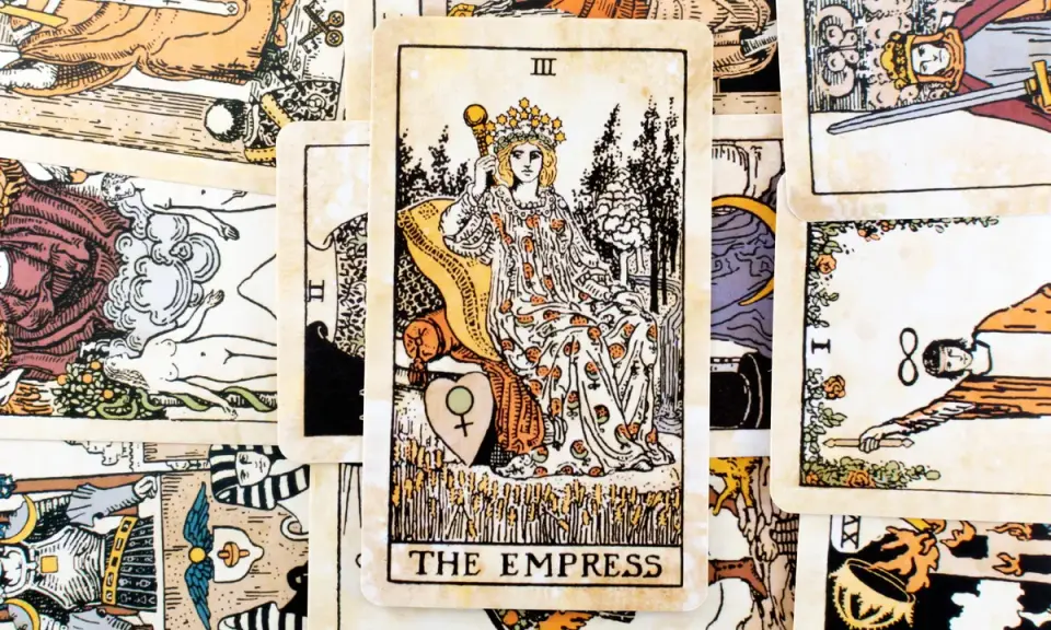 Karta Tarota "The Empress" z koroną i berłem, siedząca na tronie, otoczona innymi kartami.