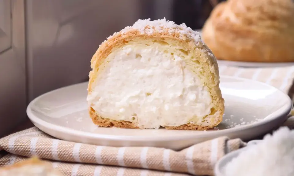Bignè ripieno di crema soffice, cosparso di zucchero a velo che ricorda un fiocco di neve.