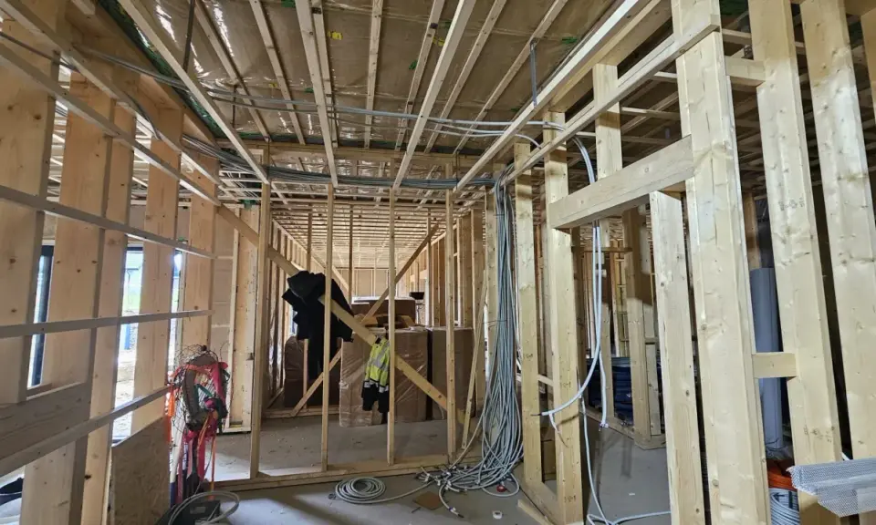 Widok wnętrza domu drewnianego w budowie. Widoczna instalacja elektryczna, drewniane ściany i stropy. Przepisy dotyczące instalacji elektrycznej w domach drewnianych są kluczowe dla bezpieczeństwa.