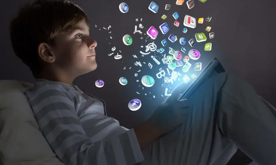 Niño de la generación alfa interactuando con iconos de aplicaciones y letras que flotan desde una tablet.
