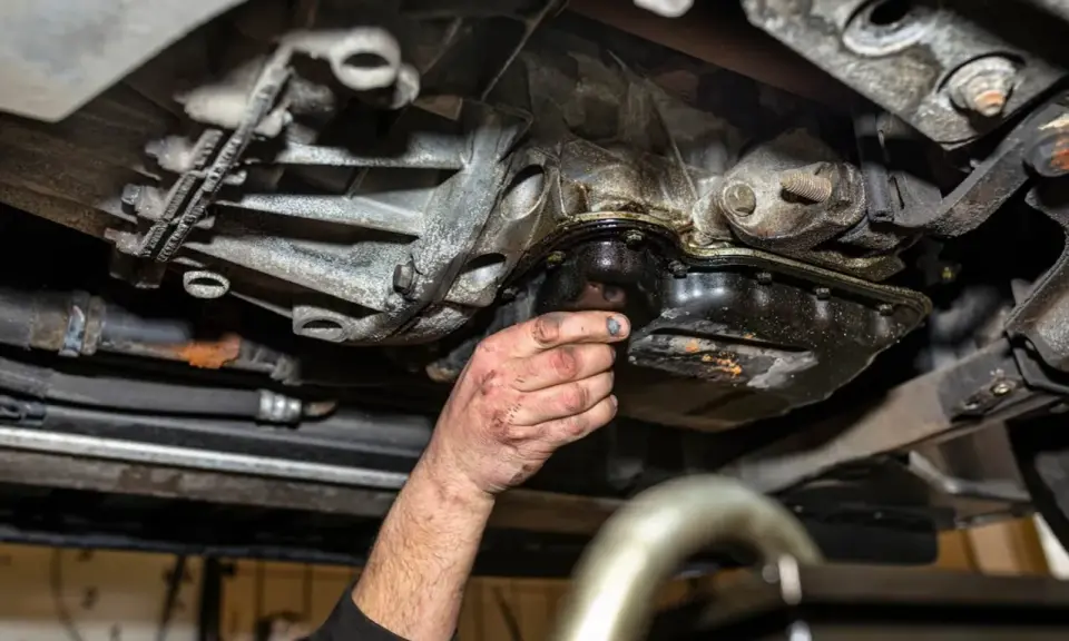 Ręka mechanika sprawdza wyciek z suchej miski olejowej.