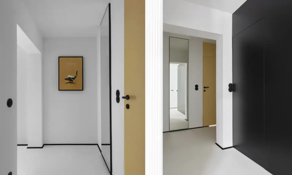 Minimalistyczny, mały przedpokój inspiracje ściany: złote i czarne drzwi, lustro, grafika z fotelem Eamesa.