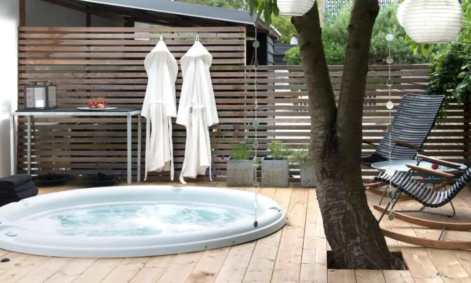 Avslappnad utomhusmiljö med jacuzzi, badrockar och bekväma stolar. Perfekt jacuzzi utomhus inspiration för en lugn stund.