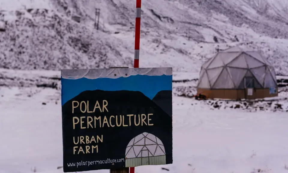 Panneau "Polar Permaculture Urban Farm" devant un dôme géodésique enneigé, rappelant la réserve mondiale de semences du Svalbard.