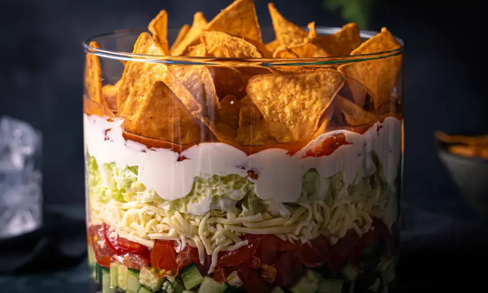 Schichtsalat im Glas: knackige Gurken, Tomaten, Käse, Salat, cremige Soße und Tortilla-Chips. Ein köstlicher nacho salat.