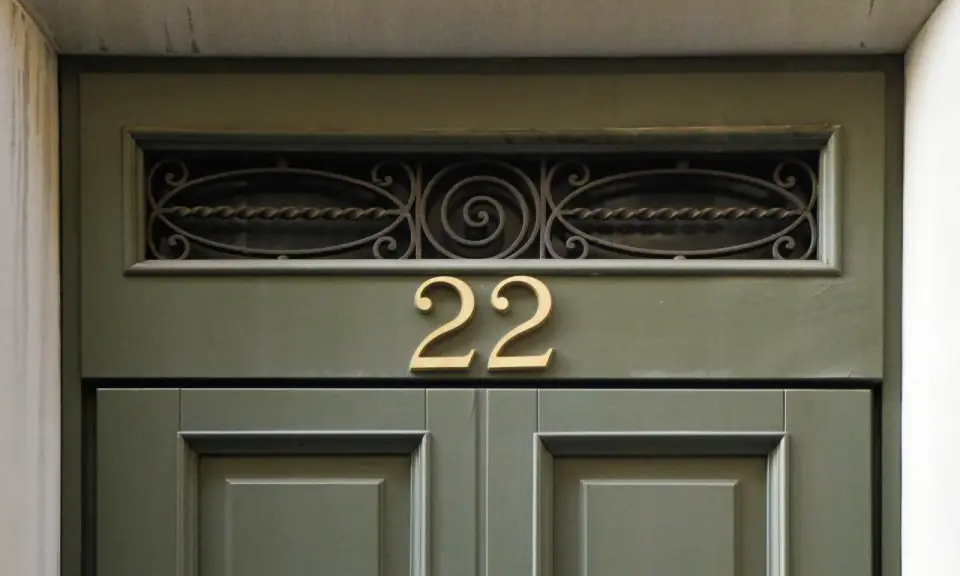 Złote **anielskie liczby** 22 na zielonych drzwiach.