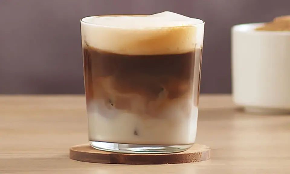 Ein erfrischender kalter Latte Macchiato mit cremiger Schaumkrone und Eiswürfeln.