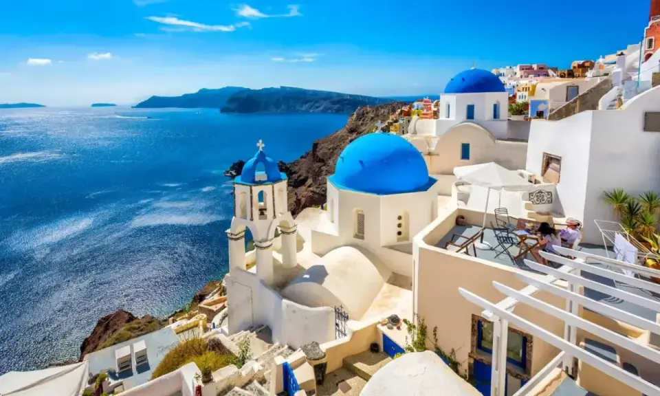 Santorini, Grecja. Białe domy z niebieskimi kopułami nad morzem. Idealne miejsce, gdzie do Grecji na wakacje.