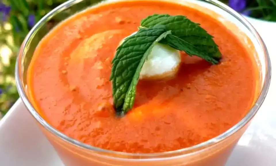 Un verre de gaspacho tomate, garni d'une feuille de menthe et d'une boule de mozzarella. Parfait pour se rafraîchir.