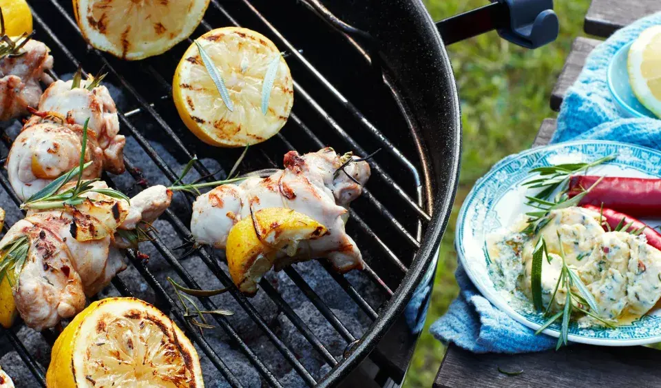 Grillad kyckling med citron och rosmarin på grillen, redo att serveras med en krämig röra och chili.