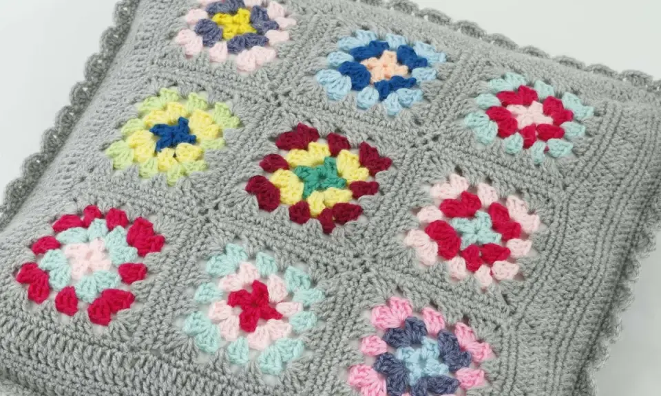 Szare szydełkowe poszewki na poduszki z kolorowymi wzorami w stylu granny square.
