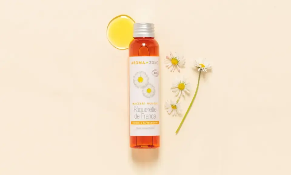 Flacon d'huile de pâquerette Aroma-Zone, avec des pâquerettes. Attention, l'huile de pâquerette danger potentiel pour certaines peaux.
