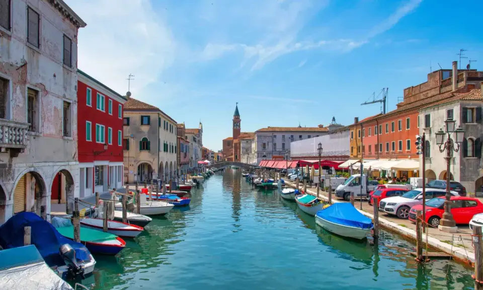 Vue d'un canal à Chioggia, Venise, avec des bateaux amarrés le long des maisons colorées.