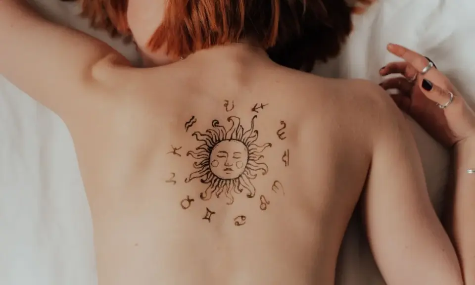 Tatuaż na plecach przedstawia słońce otoczone znakami zodiaku. Baran w ascendencie, symbolizujący energię i początek, jest centralnym punktem.
