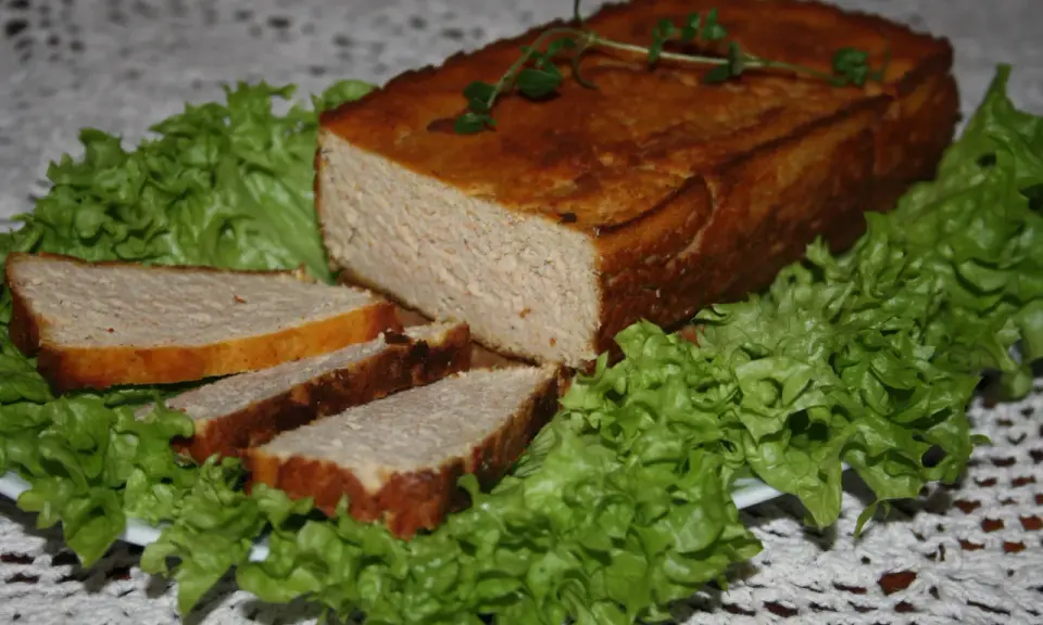 Pyszny pasztet drobiowy z wątróbką, pokrojony w plastry, podany na liściach sałaty. Idealny na kanapki.