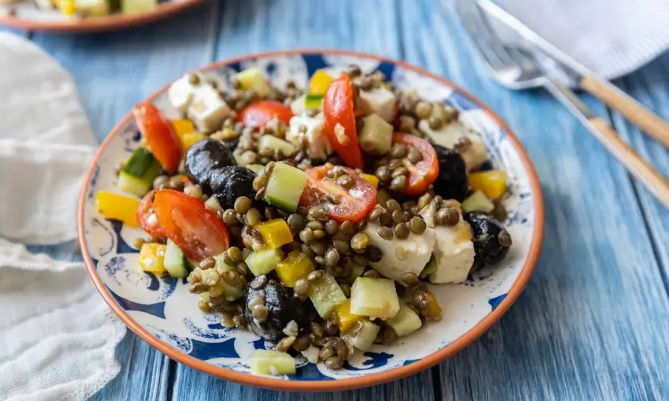 Salade colorée de lentilles vertes avec tomates, concombre, olives noires et feta. Un plat frais et savoureux.