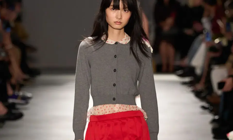 Modella con cardigan grigio e gonna rosso vivo, un contrasto audace.